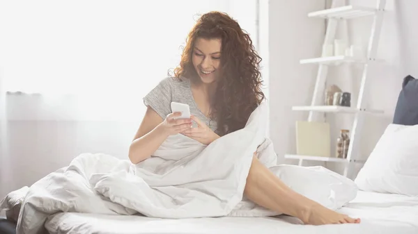 Mutlu Genç Bir Kadın Yatak Odasında Akıllı Telefondan Mesajlaşıyor — Stok fotoğraf