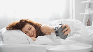 cheerful young woman holding retro alarm clock clipart