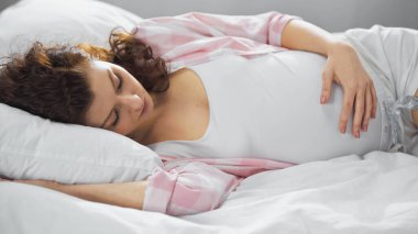 Genç hamile kadın yatakta uyuyor.