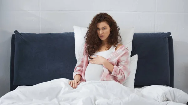 Gravid Kvinna Vidrör Magen Medan Sitter Sängen — Stockfoto