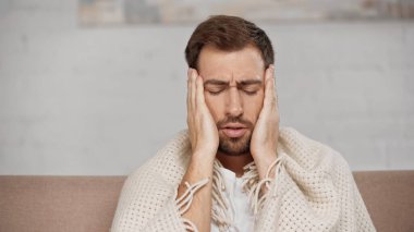 bearded man suffering from migraine at home