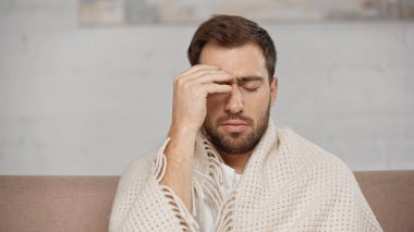 bearded man suffering from headache at home