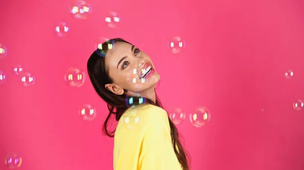 Happy Young Adult Woman Yellow Blouse Soap Bubbles Pink Background — Stockfoto