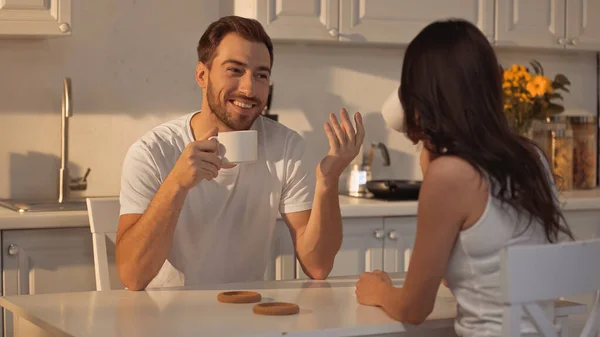 Happy Man Holding Cup Talking Blurred Brunette Girlfriend — Φωτογραφία Αρχείου