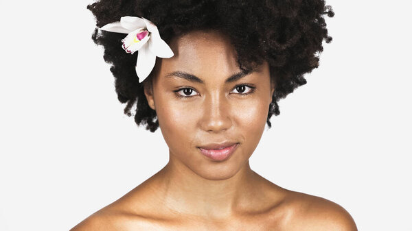 African american woman with perfect skin and flower in hair isolated on grey 