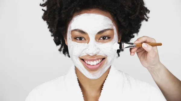 Hombre Con Cepillo Aplicando Máscara Cara Alegre Mujer Afroamericana Aislada —  Fotos de Stock