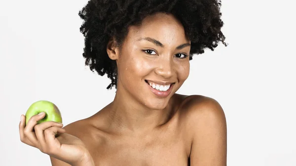 面带微笑的非洲裔美国女人 皮肤洁白 看着相机 手里拿着用灰色隔开的绿色苹果 — 图库照片
