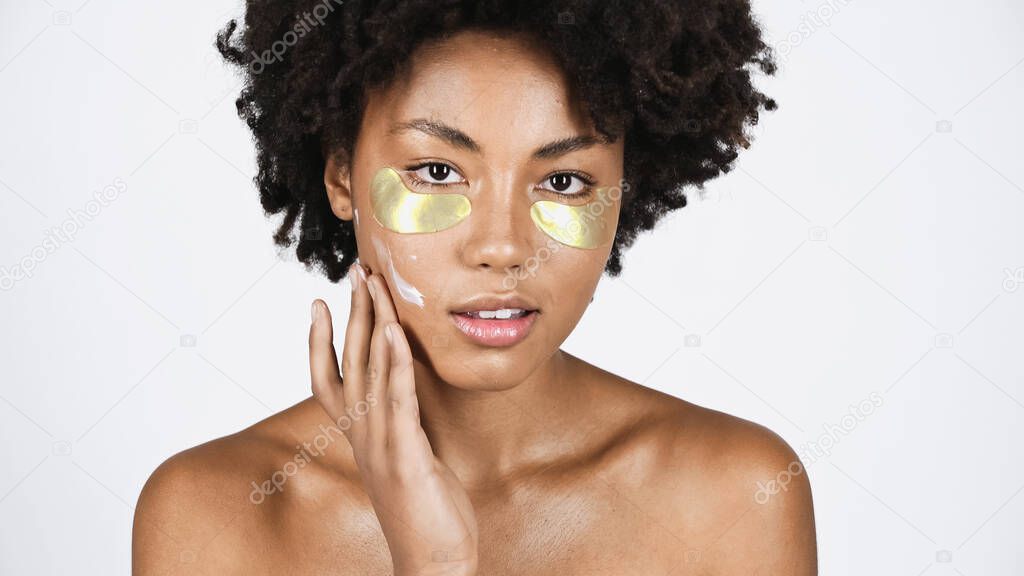 African american woman with eye patches applying cream on face isolated on grey 