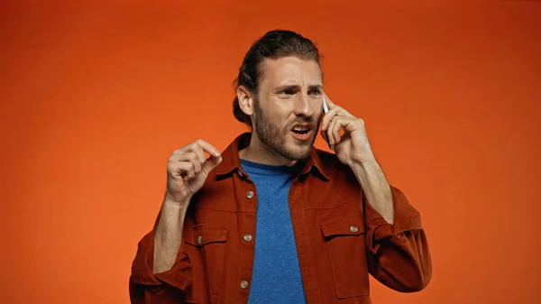Mécontent jeune homme parlant sur téléphone mobile sur orange — Photo de stock