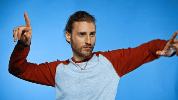 Bearded young man pointing with fingers on blue — Stock Photo