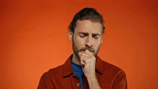 Young bearded man thinking on orange background — Stock Photo