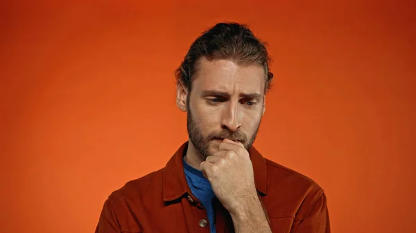 Young pensive man thinking on orange background — Stock Photo