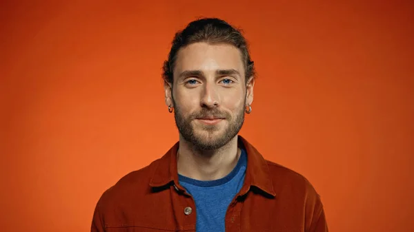 Pleased bearded man looking at camera on orange background — Stock Photo