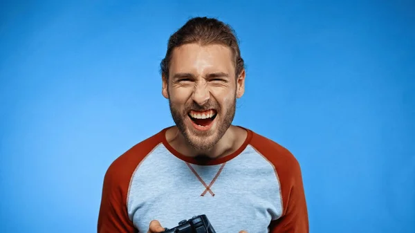 KYIV, UKRAINE - NOVEMBER 24, 2020: bearded man holding joystick while laughing on blue — Stock Photo