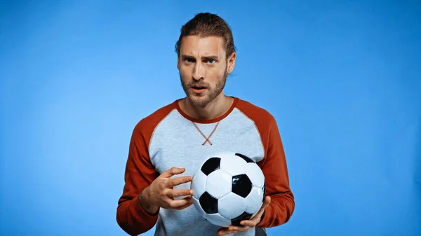 В шоке футбольный болельщик держа футбольный мяч на синий — стоковое фото