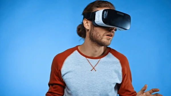 Surprised young man in virtual reality headset on blue — Stock Photo