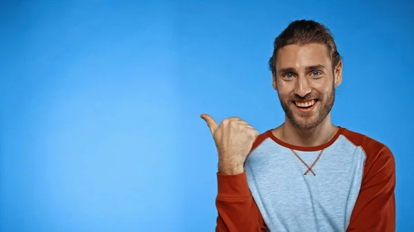 Joyful man pointing with thumb on blue — Stock Photo