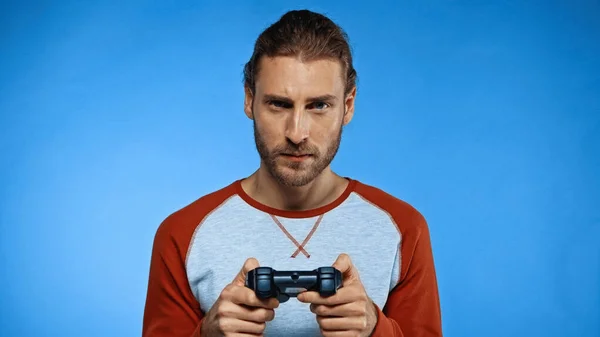KYIV, UKRAINE - NOVEMBER 24, 2020: bearded man holding joystick and playing video game on blue — Stock Photo