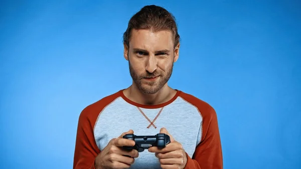 KYIV, UCRAINA - 24 NOVEMBRE 2020: giovane che tiene il joystick e gioca ai videogiochi in blu — Foto stock