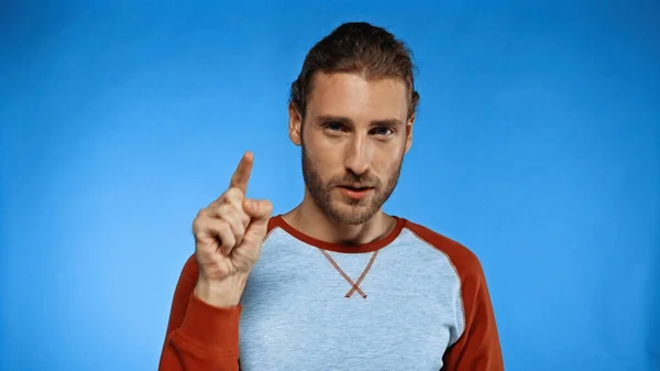 Bearded young man pointing with finger on blue — Stock Photo