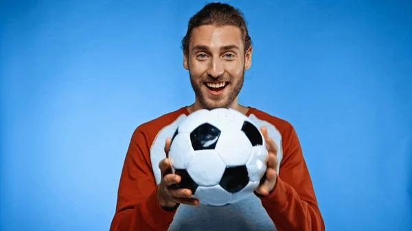 Положительный футбольный болельщик проведение футбольный мяч на синий — стоковое фото