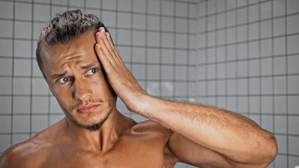 Torse nu jeune homme fixant les cheveux dans la salle de bain — Photo de stock