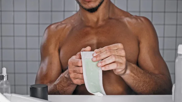 Обрізаний вид без сорочки чоловік тримає воскову смужку на грудях у ванній — стокове фото