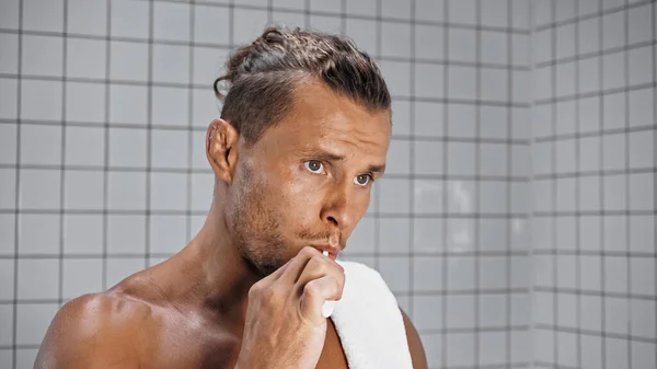 Homme barbu brossant les dents et regardant loin dans la salle de bain — Photo de stock