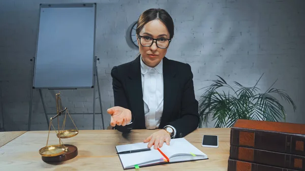 Insurance agent pointing with hand near notebook, smartphone and scales in office — Stock Photo