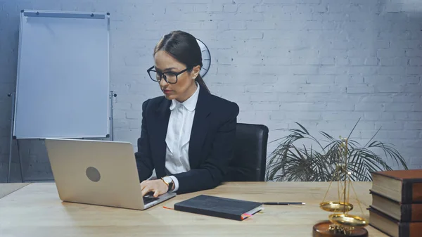 Versicherungsvertreter mit Laptop neben Notizbuch, Büchern und Waagen im unscharfen Vordergrund — Stockfoto