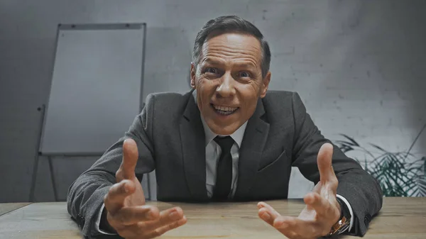 Sorrindo agente de seguros olhando para a câmera enquanto sentado à mesa no escritório — Fotografia de Stock