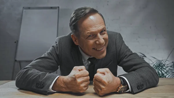 Smiling insurance agent with hands in fists looking at camera in office — Stock Photo