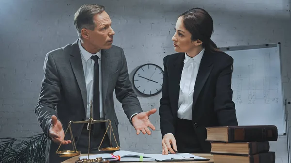 Insurance agents talking near clipboard, books and scales on blurred foreground — Stock Photo