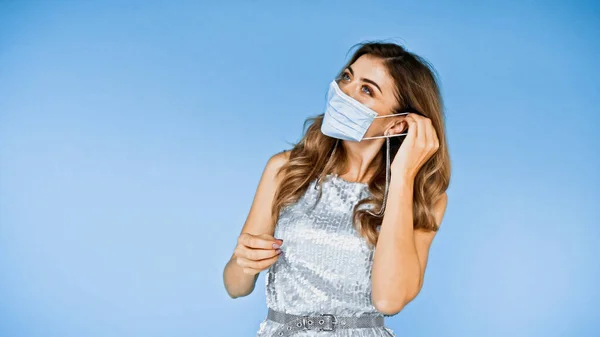 Mulher com cabelo ondulado usando máscara médica isolada em azul — Fotografia de Stock