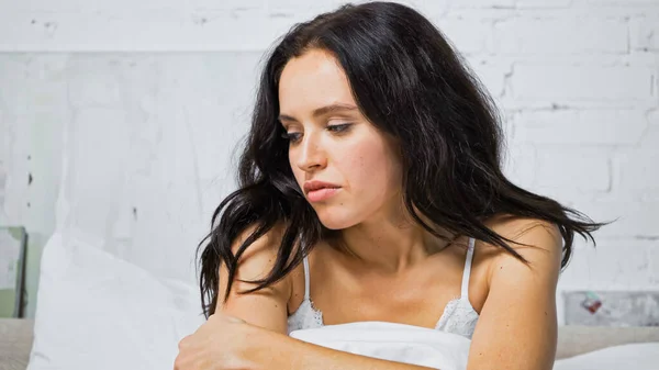 Offended brunette woman sitting in bedroom in morning — Stock Photo