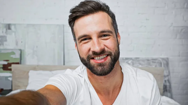 Homem barbudo feliz sorrindo para a câmera no quarto — Fotografia de Stock