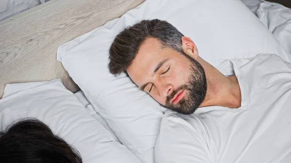 Hombre barbudo durmiendo en ropa de cama blanca en casa - foto de stock