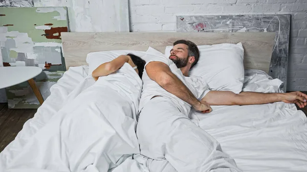 Jeune couple dormant sous couverture blanche à la maison — Photo de stock