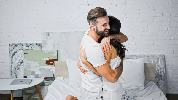 Felice uomo barbuto abbracciare fidanzata in camera da letto — Foto stock