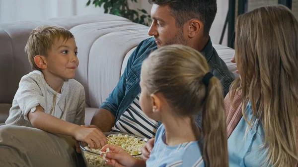 Garçon prenant pop-corn près de la famille sur le premier plan flou à la maison — Photo de stock