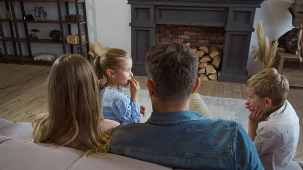 Kinder sitzen neben Eltern auf verschwommenem Vordergrund im Wohnzimmer — Stockfoto