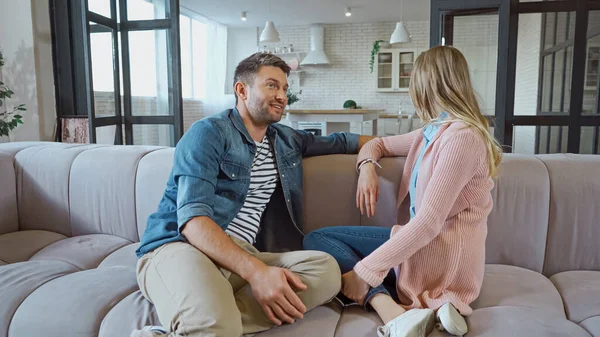 Sorrindo marido sentado perto da esposa no sofá em casa — Fotografia de Stock