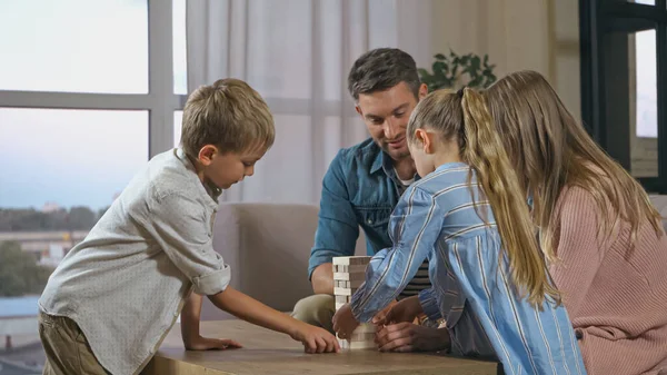 Enfants et parents jouant jeu de blocs de bois à la maison — Photo de stock