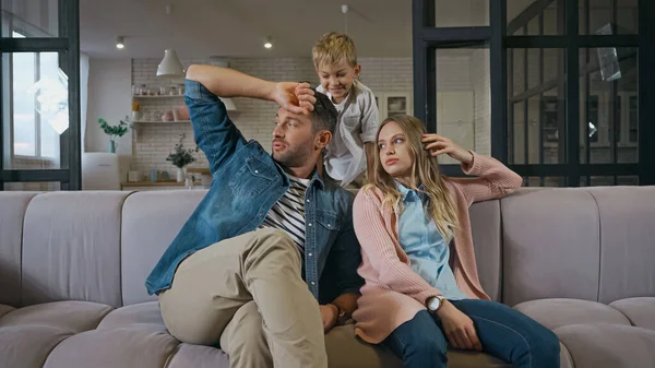 Smiling boy sitting near parents on couch at home — Stock Photo