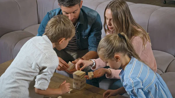 Family with kids playing wood blocks game at home — Stock Photo