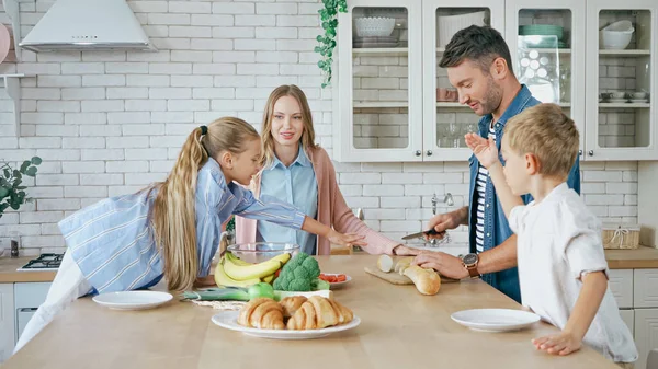 Família de pé perto de comida e croissants na mesa na cozinha — Fotografia de Stock