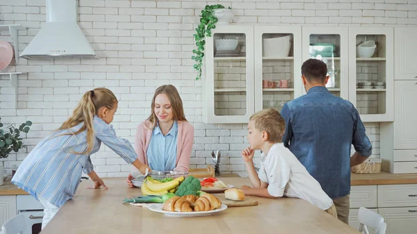 Familie mit Kindern steht neben Essen und Gebäck auf Küchentisch — Stockfoto