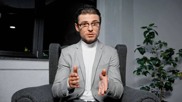 Young businessman in suit and eyeglasses talking at camera during video chat — Stock Photo