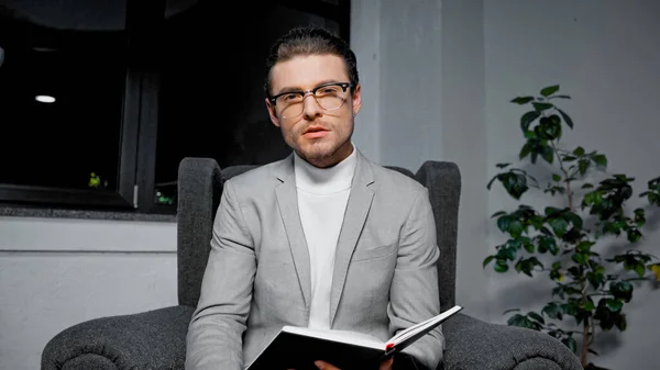 Homme d'affaires avec copybook regardant la caméra dans le bureau — Photo de stock