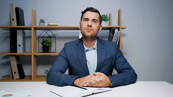 Businessman looking at camera near notebook and pen — Stock Photo